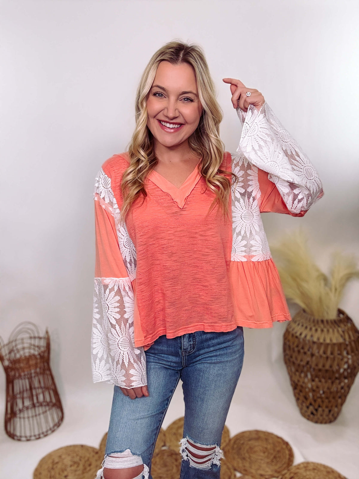 POL Clothing Coral Peach Boho Lace Flare Sleeve V-Neck Top featuring sheer floral lace sleeves, bunched side details, and a relaxed fit, made from a blend of nylon, rayon, and spandex.