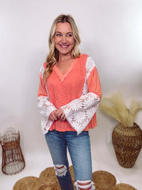 POL Clothing Coral Peach Boho Lace Flare Sleeve V-Neck Top featuring sheer floral lace sleeves, bunched side details, and a relaxed fit, made from a blend of nylon, rayon, and spandex.