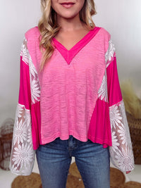 POL Clothing Hot Pink Boho Lace Flare Sleeve V-Neck Top featuring sheer floral lace sleeves, bunched side details, and a relaxed fit, made from a blend of nylon, rayon, and spandex.