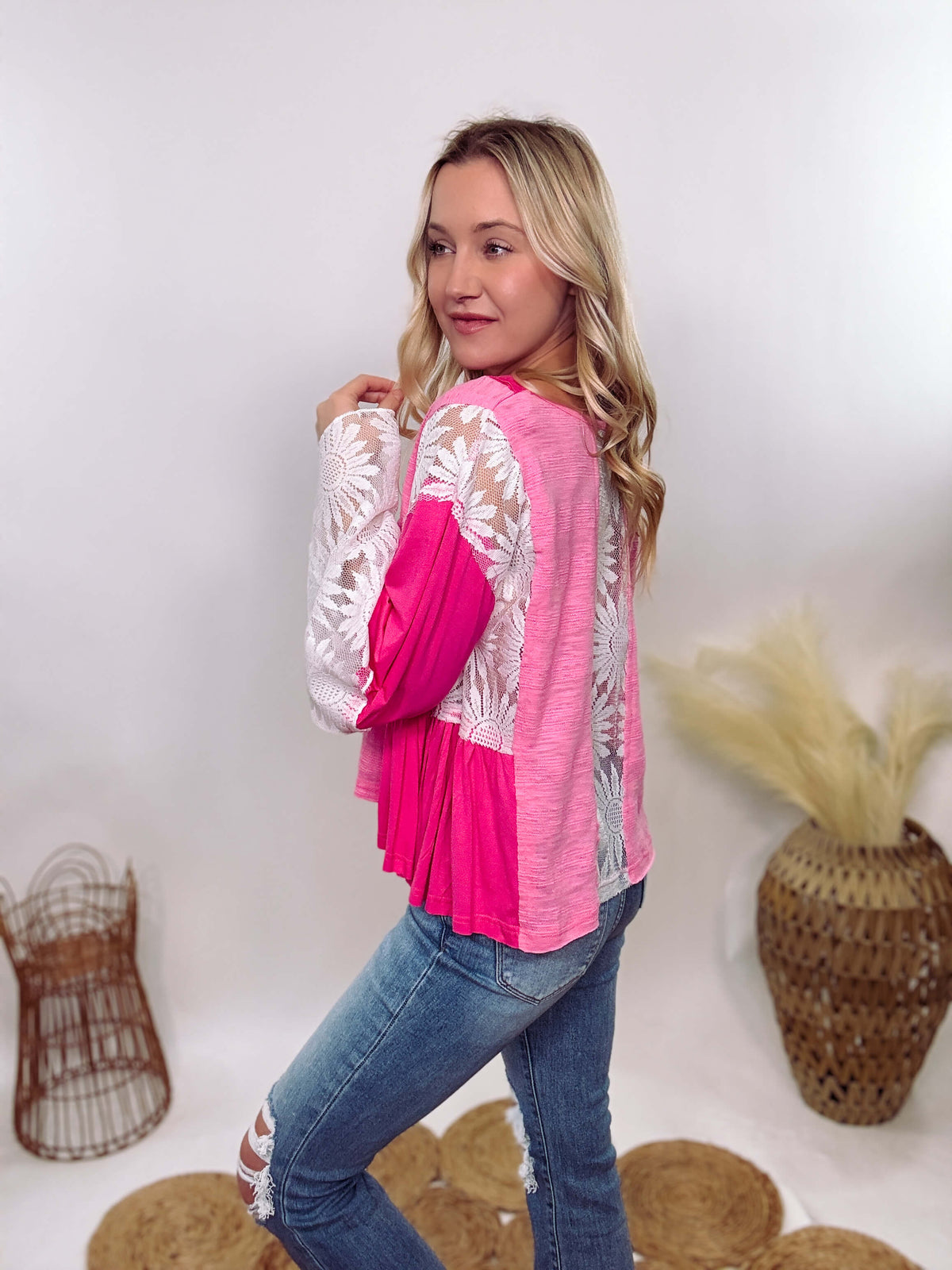 POL Clothing Hot Pink Boho Lace Flare Sleeve V-Neck Top featuring sheer floral lace sleeves, bunched side details, and a relaxed fit, made from a blend of nylon, rayon, and spandex.