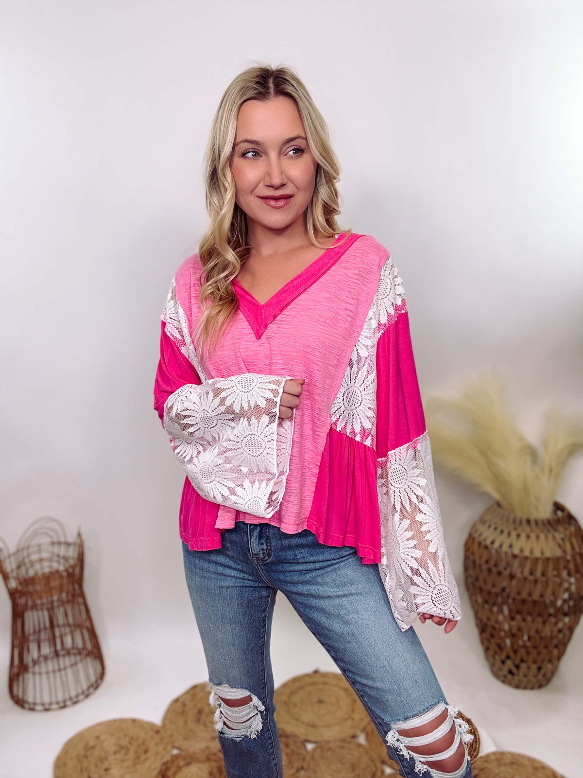 POL Clothing Hot Pink Boho Lace Flare Sleeve V-Neck Top featuring sheer floral lace sleeves, bunched side details, and a relaxed fit, made from a blend of nylon, rayon, and spandex.