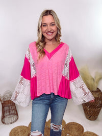 POL Clothing Hot Pink Boho Lace Flare Sleeve V-Neck Top featuring sheer floral lace sleeves, bunched side details, and a relaxed fit, made from a blend of nylon, rayon, and spandex.