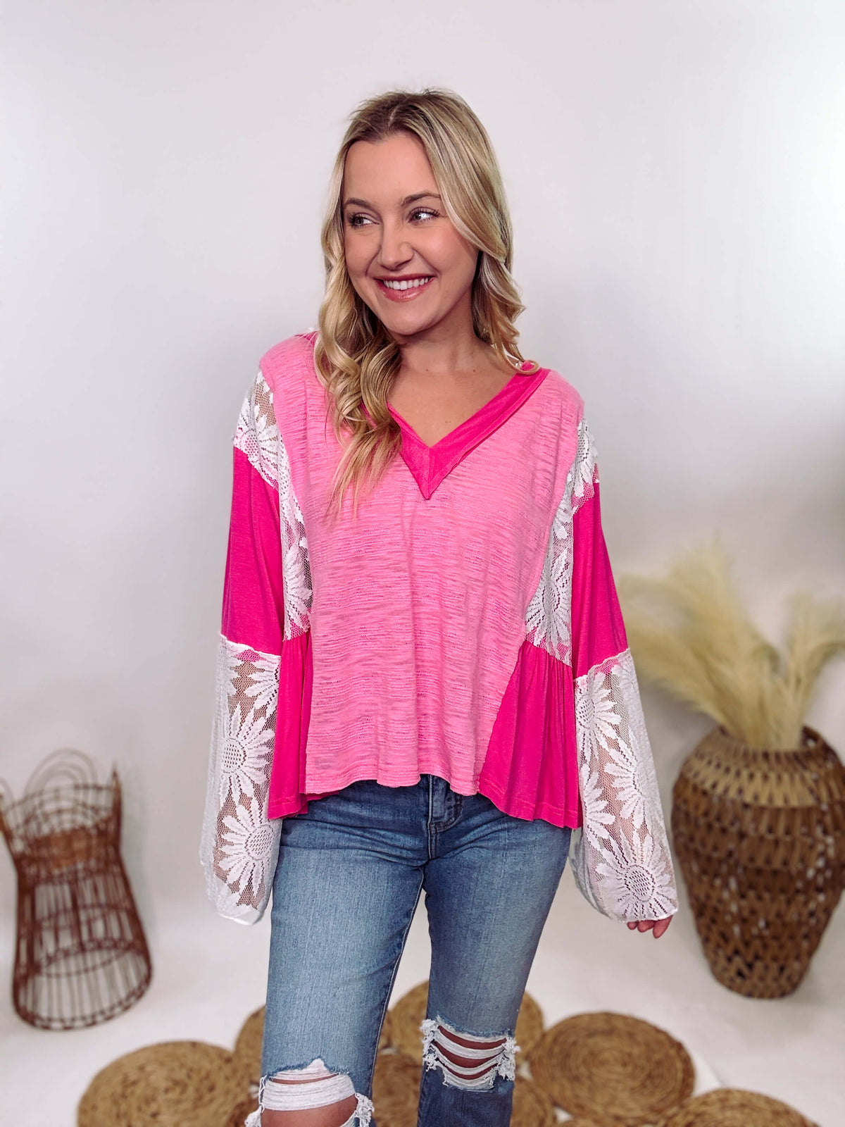 POL Clothing Hot Pink Boho Lace Flare Sleeve V-Neck Top featuring sheer floral lace sleeves, bunched side details, and a relaxed fit, made from a blend of nylon, rayon, and spandex.