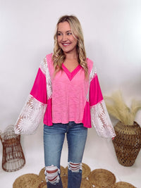 POL Clothing Hot Pink Boho Lace Flare Sleeve V-Neck Top featuring sheer floral lace sleeves, bunched side details, and a relaxed fit, made from a blend of nylon, rayon, and spandex.