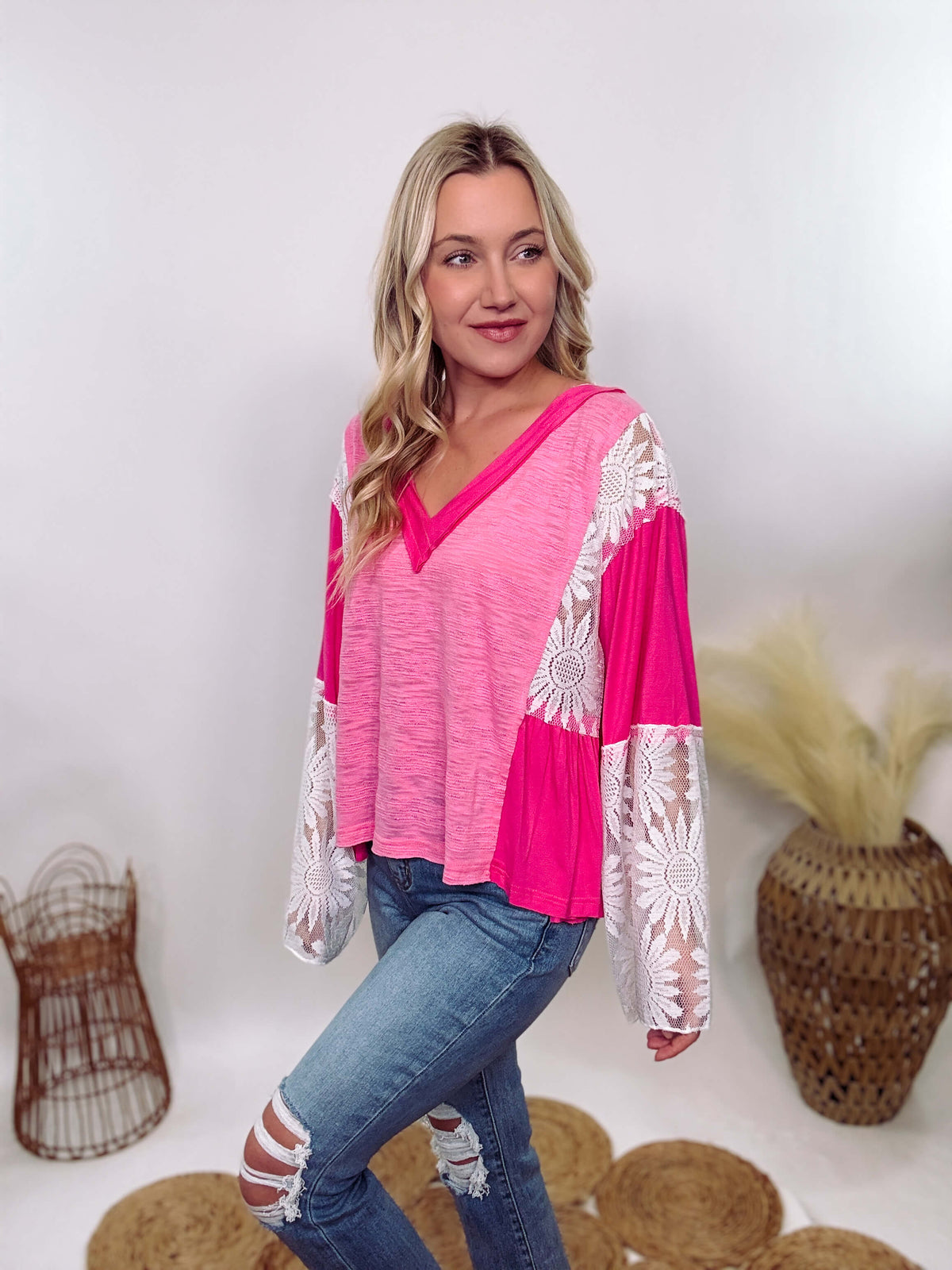 POL Clothing Hot Pink Boho Lace Flare Sleeve V-Neck Top featuring sheer floral lace sleeves, bunched side details, and a relaxed fit, made from a blend of nylon, rayon, and spandex.