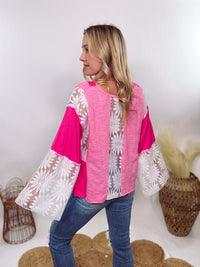 POL Clothing Hot Pink Boho Lace Flare Sleeve V-Neck Top featuring sheer floral lace sleeves, bunched side details, and a relaxed fit, made from a blend of nylon, rayon, and spandex.