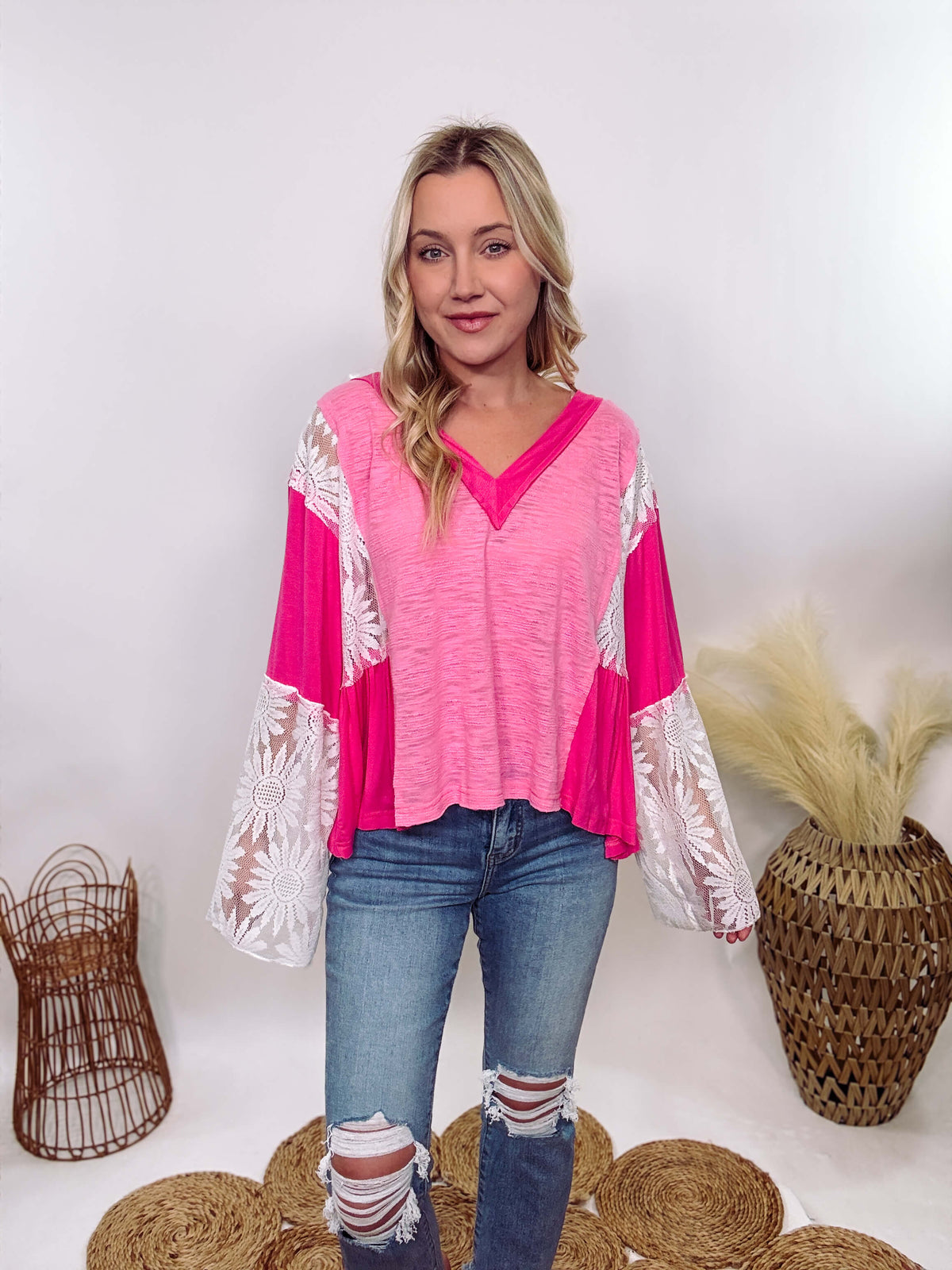 POL Clothing Hot Pink Boho Lace Flare Sleeve V-Neck Top featuring sheer floral lace sleeves, bunched side details, and a relaxed fit, made from a blend of nylon, rayon, and spandex.