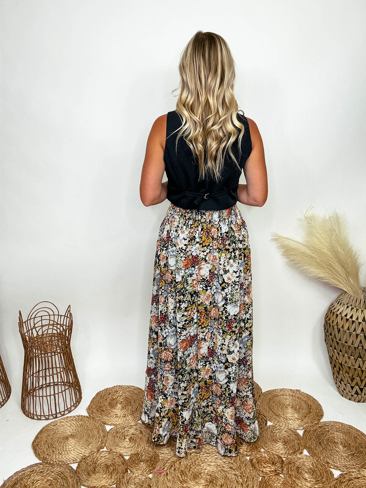 Promesa Vintage Floral Boho Maxi Skirt with Front Slit and Smocked Stretchy Waistband, Styled with Black Vest and White Booties at Bmaes Boutique