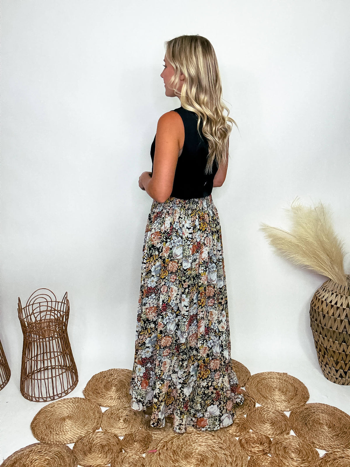 Promesa Vintage Floral Boho Maxi Skirt with Front Slit and Smocked Stretchy Waistband, Styled with Black Vest and White Booties at Bmaes Boutique