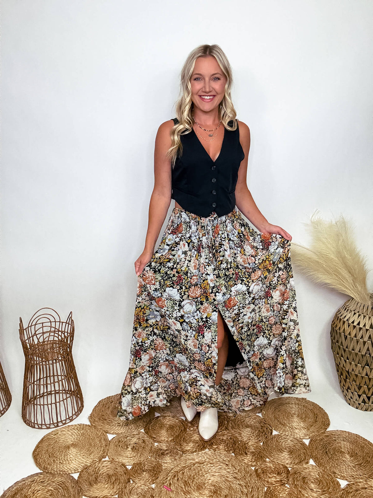 Promesa Vintage Floral Boho Maxi Skirt with Front Slit and Smocked Stretchy Waistband, Styled with Black Vest and White Booties at Bmaes Boutique