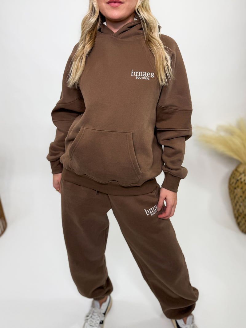 Chocolate brown fleece-lined luxury lounge Bmaes hoodie with embroidered Bmaes Boutique logo, drop shoulders, kangaroo pocket, and ribbed details. Perfect for cozy lounging or pairing with the matching joggers for a stylish, warm set from Bmaes Boutique.