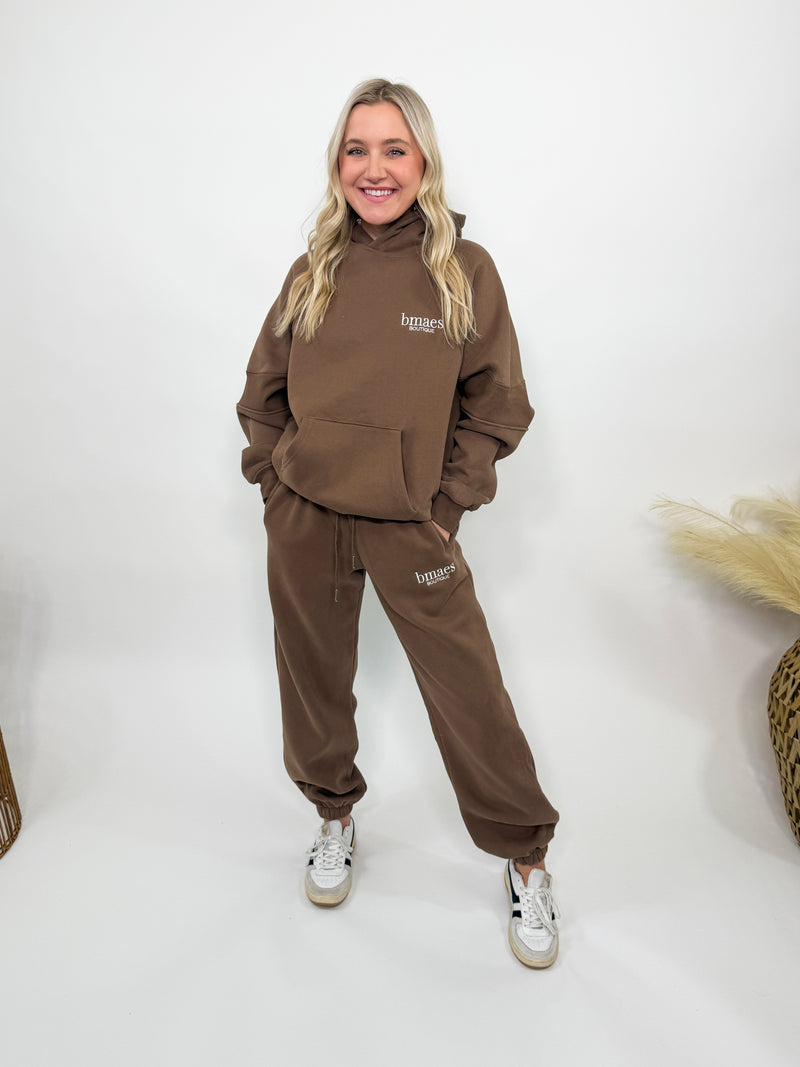 Chocolate brown fleece-lined luxury lounge Bmaes hoodie with embroidered Bmaes Boutique logo, drop shoulders, kangaroo pocket, and ribbed details. Perfect for cozy lounging or pairing with the matching joggers for a stylish, warm set from Bmaes Boutique.