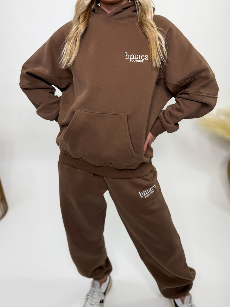 Chocolate brown fleece-lined luxury lounge Bmaes hoodie with embroidered Bmaes Boutique logo, drop shoulders, kangaroo pocket, and ribbed details. Perfect for cozy lounging or pairing with the matching joggers for a stylish, warm set from Bmaes Boutique.