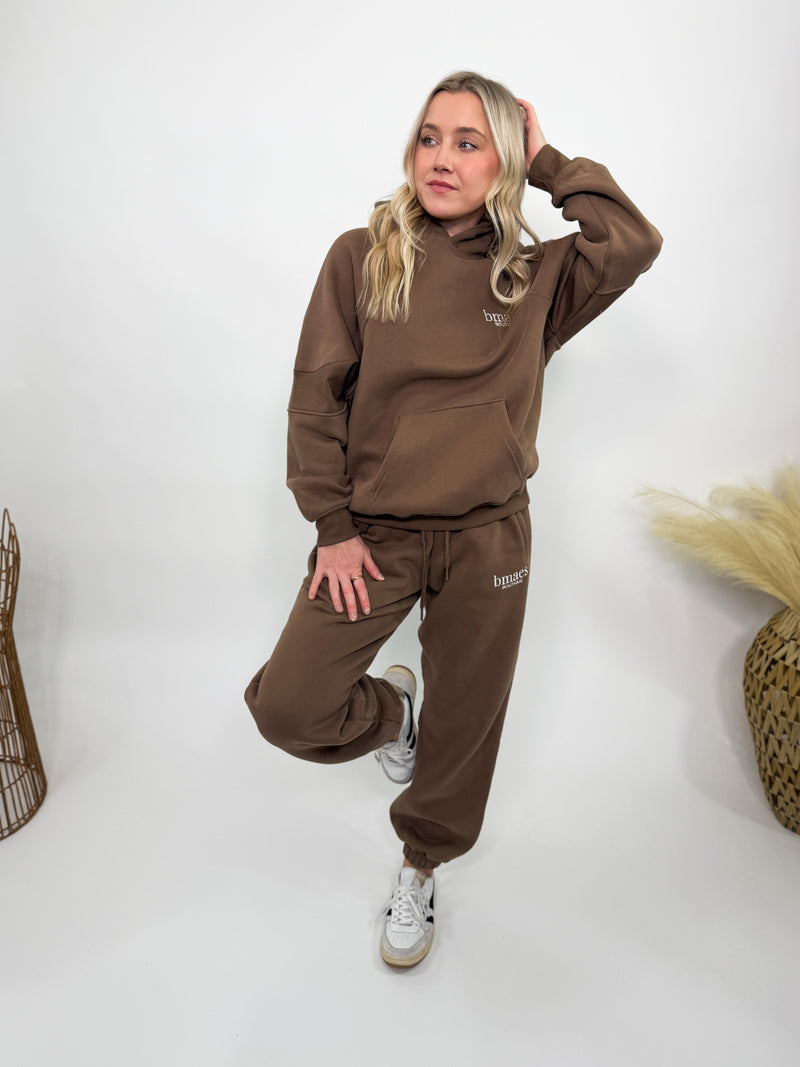 Chocolate brown fleece-lined luxury lounge Bmaes hoodie with embroidered Bmaes Boutique logo, drop shoulders, kangaroo pocket, and ribbed details. Perfect for cozy lounging or pairing with the matching joggers for a stylish, warm set from Bmaes Boutique.