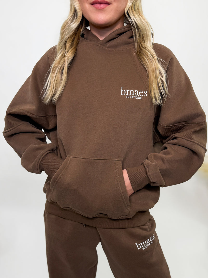 Chocolate brown fleece-lined luxury lounge Bmaes hoodie with embroidered Bmaes Boutique logo, drop shoulders, kangaroo pocket, and ribbed details. Perfect for cozy lounging or pairing with the matching joggers for a stylish, warm set from Bmaes Boutique.