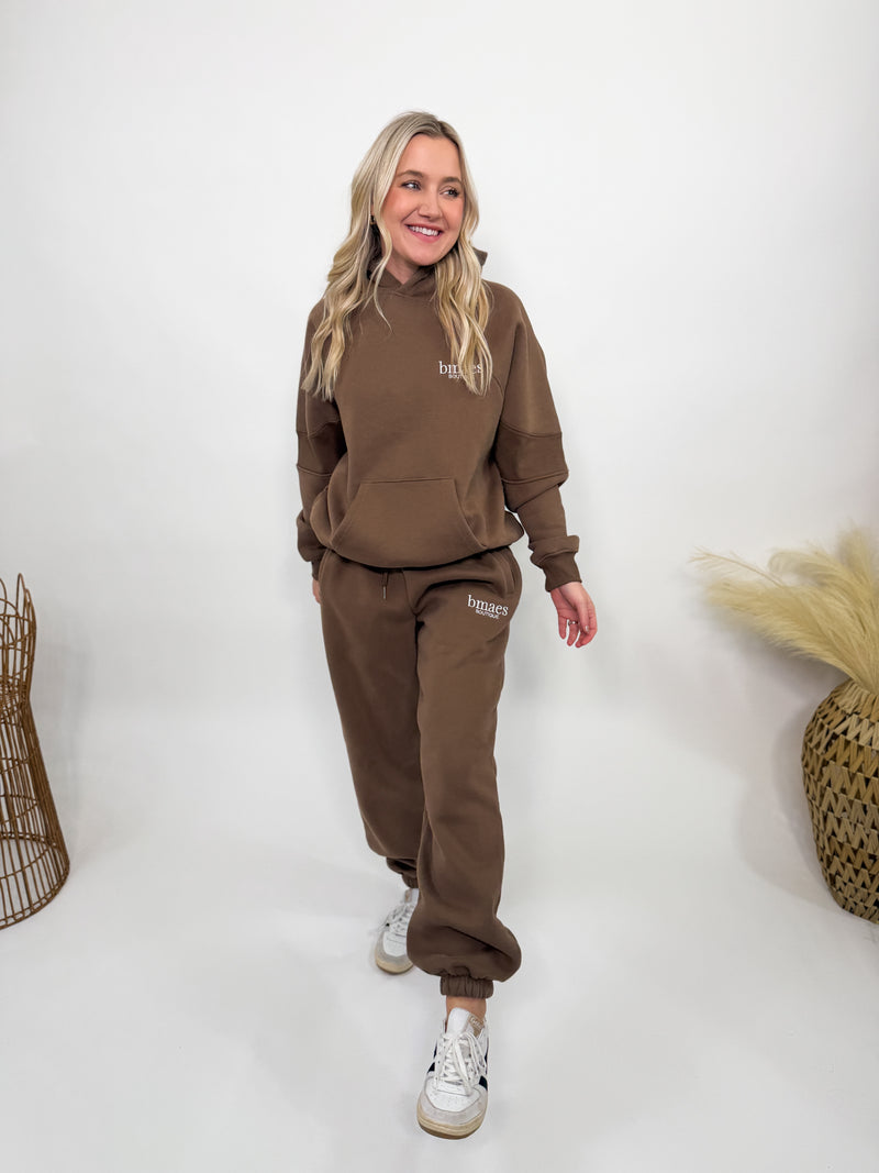 Chocolate brown fleece-lined luxury lounge Bmaes hoodie with embroidered Bmaes Boutique logo, drop shoulders, kangaroo pocket, and ribbed details. Perfect for cozy lounging or pairing with the matching joggers for a stylish, warm set from Bmaes Boutique.