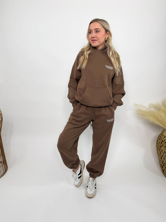 Chocolate brown fleece-lined luxury lounge Bmaes hoodie with embroidered Bmaes Boutique logo, drop shoulders, kangaroo pocket, and ribbed details. Perfect for cozy lounging or pairing with the matching joggers for a stylish, warm set from Bmaes Boutique.