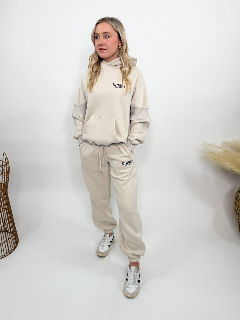 Cream fleece-lined luxury lounge Bmaes hoodie with embroidered Bmaes Boutique logo, drop shoulders, kangaroo pocket, and ribbed details. Perfect for cozy lounging or pairing with the matching joggers for a stylish, warm set from Bmaes Boutique.