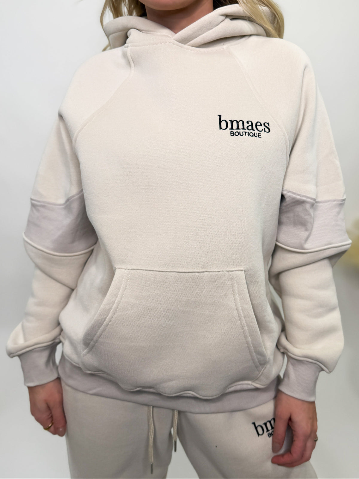 Cream fleece-lined luxury lounge Bmaes hoodie with embroidered Bmaes Boutique logo, drop shoulders, kangaroo pocket, and ribbed details. Perfect for cozy lounging or pairing with the matching joggers for a stylish, warm set from Bmaes Boutique.