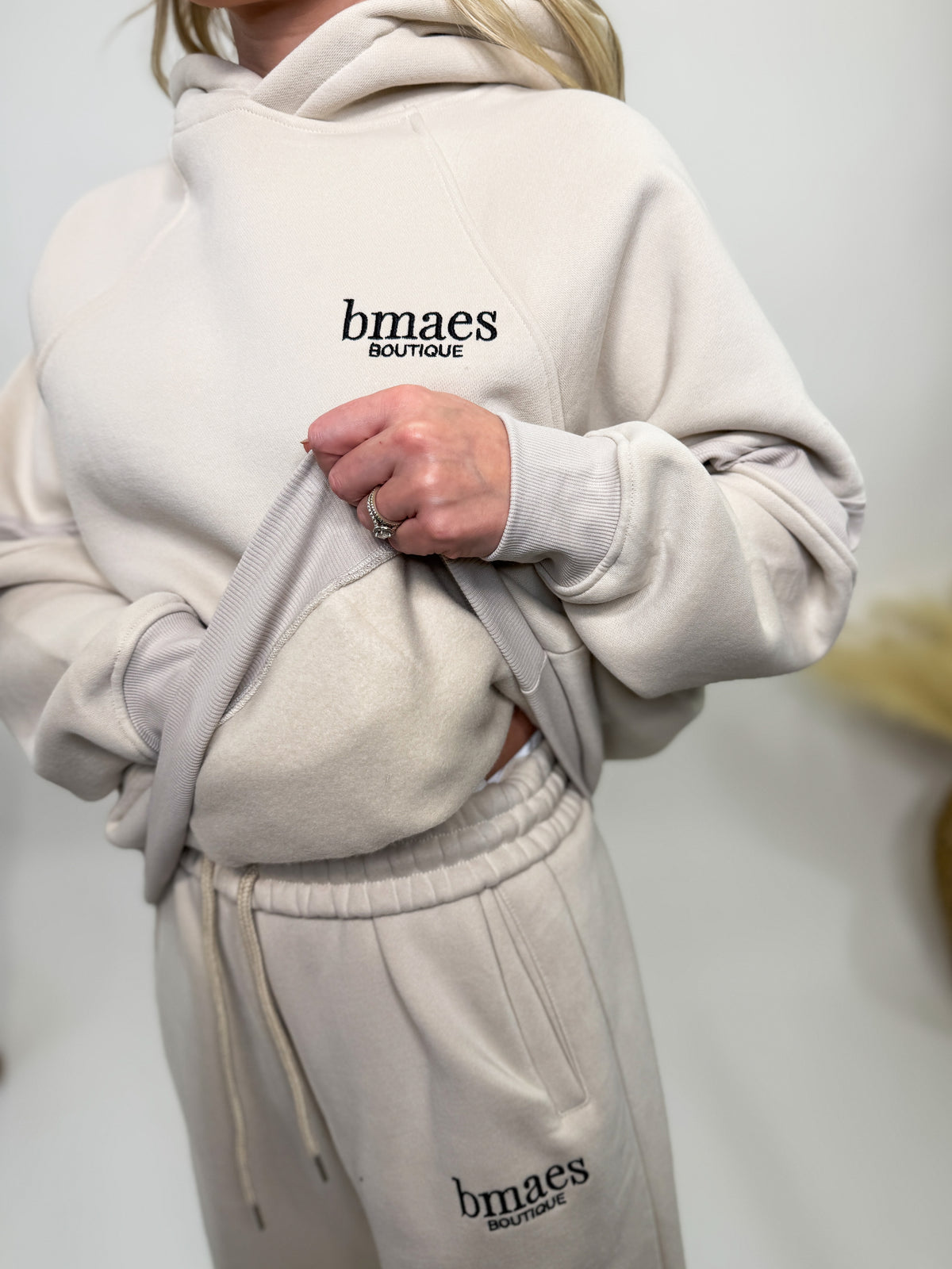 Cream fleece-lined luxury lounge Bmaes hoodie with embroidered Bmaes Boutique logo, drop shoulders, kangaroo pocket, and ribbed details. Perfect for cozy lounging or pairing with the matching joggers for a stylish, warm set from Bmaes Boutique.