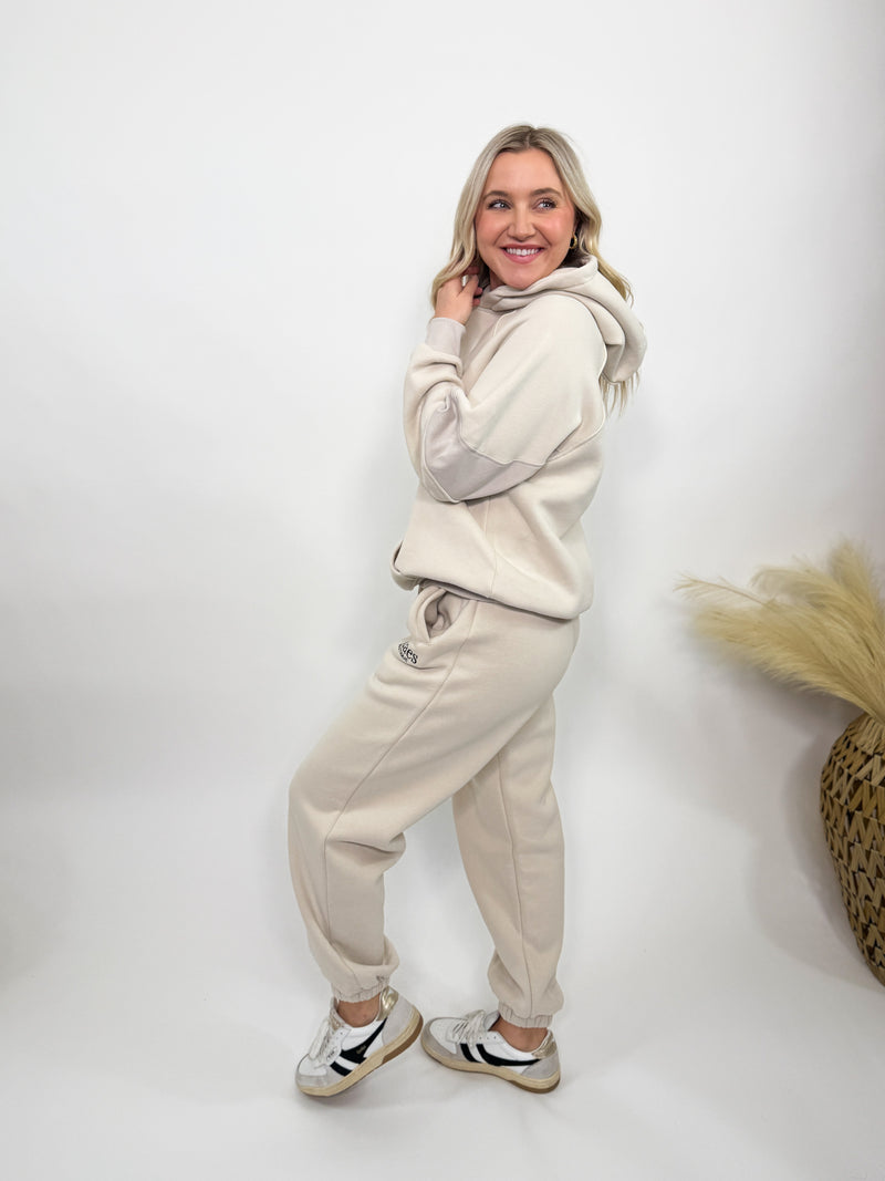 Cream fleece-lined luxury lounge Bmaes hoodie with embroidered Bmaes Boutique logo, drop shoulders, kangaroo pocket, and ribbed details. Perfect for cozy lounging or pairing with the matching joggers for a stylish, warm set from Bmaes Boutique.