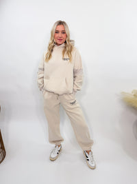 Cream fleece-lined luxury lounge Bmaes hoodie with embroidered Bmaes Boutique logo, drop shoulders, kangaroo pocket, and ribbed details. Perfect for cozy lounging or pairing with the matching joggers for a stylish, warm set from Bmaes Boutique.