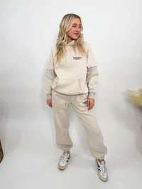 Cream fleece-lined luxury lounge Bmaes hoodie with embroidered Bmaes Boutique logo, drop shoulders, kangaroo pocket, and ribbed details. Perfect for cozy lounging or pairing with the matching joggers for a stylish, warm set from Bmaes Boutique.