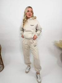 Cream fleece-lined luxury lounge Bmaes hoodie with embroidered Bmaes Boutique logo, drop shoulders, kangaroo pocket, and ribbed details. Perfect for cozy lounging or pairing with the matching joggers for a stylish, warm set from Bmaes Boutique.