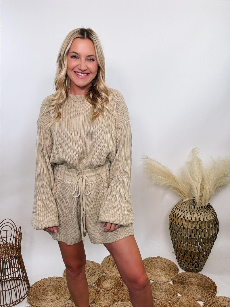 Creamy taupe long sleeve sweater romper by Mable, adjustable waist, styled with boots for fall and winter