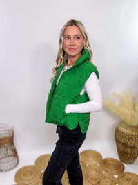 Vibrant green padded puffer vest with side slits and a zip-up front, perfect for layering and staying warm.