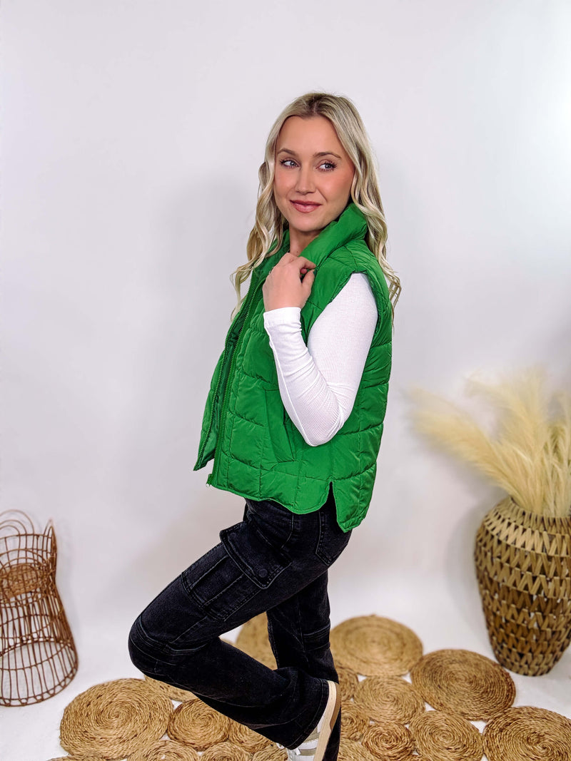 Vibrant green padded puffer vest with side slits and a zip-up front, perfect for layering and staying warm.