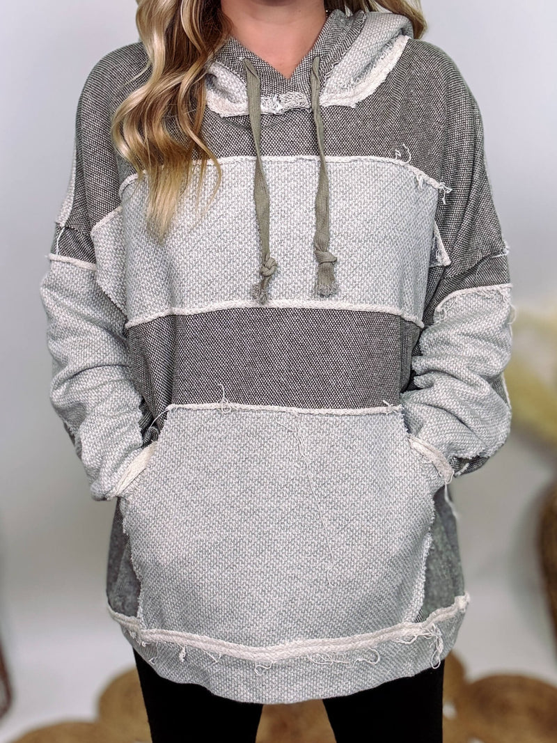 Grey olive patchwork oversized hoodie by Oli & Hali with contrast patchwork sleeves, drawstring hood, front kangaroo pocket, and exposed raw hems. Cozy and stylish design for everyday wear.