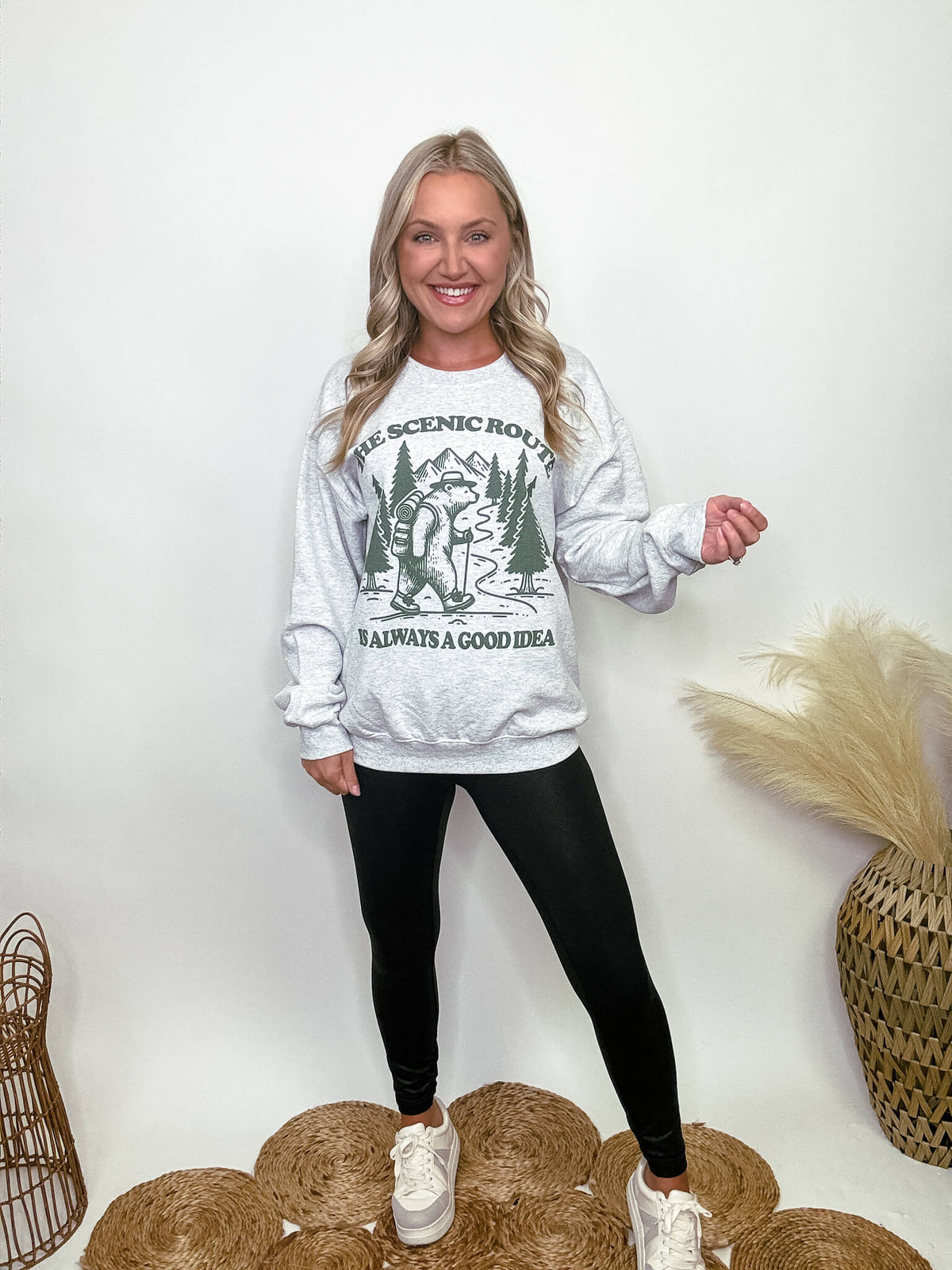 Heather grey fleece lined sweatshirt with a bear hiking graphic and the text 'The scenic route is always a good idea.' Perfect for fall outdoor activities. Model Brooke is 5'4" wearing size small.