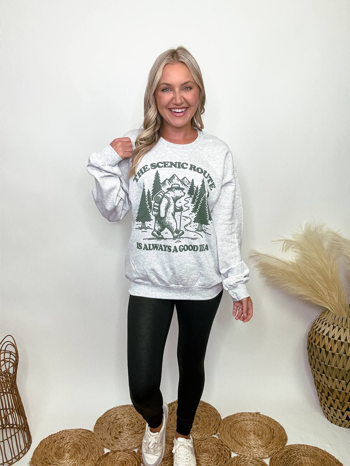 Heather grey fleece lined sweatshirt with a bear hiking graphic and the text 'The scenic route is always a good idea.' Perfect for fall outdoor activities. Model Brooke is 5'4" wearing size small.