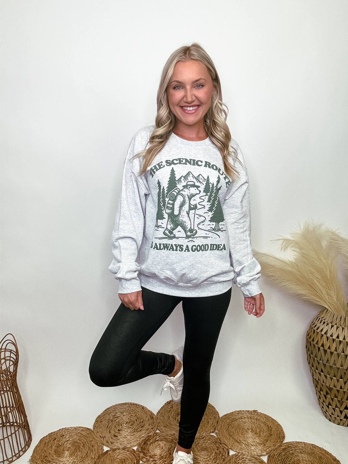 Heather grey fleece lined sweatshirt with a bear hiking graphic and the text 'The scenic route is always a good idea.' Perfect for fall outdoor activities. Model Brooke is 5'4" wearing size small.