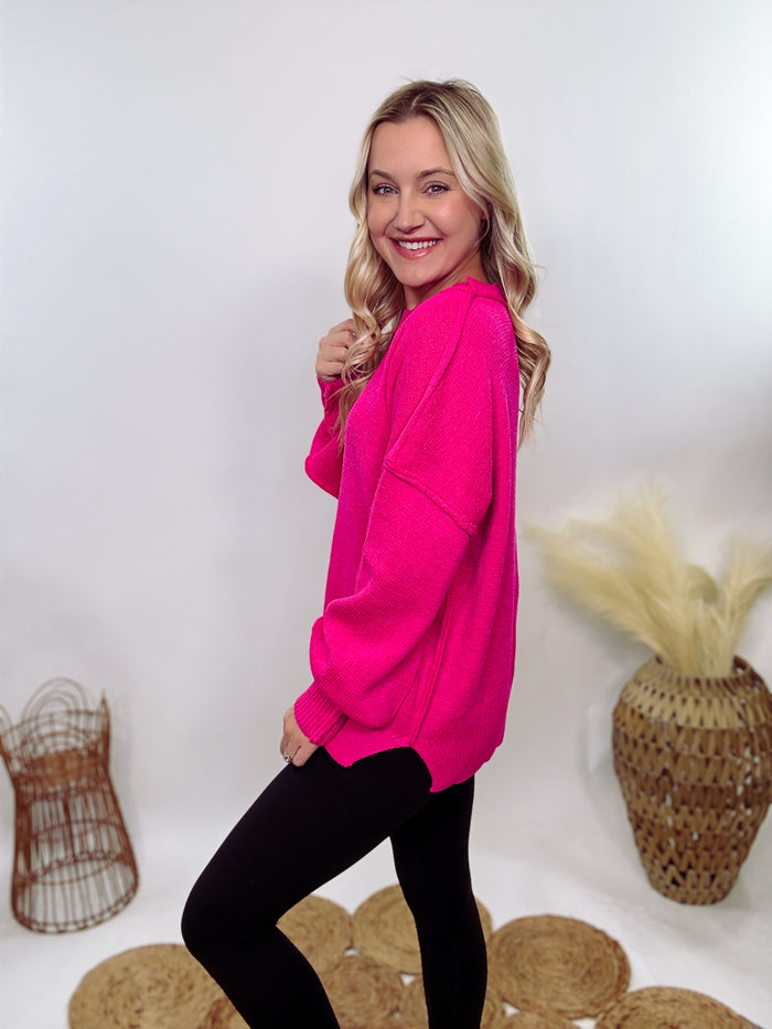 Hot pink oversized sweater with exposed seams, side slits, and a ribbed hem. Cozy, stylish, and perfect for brightening up your winter wardrobe.