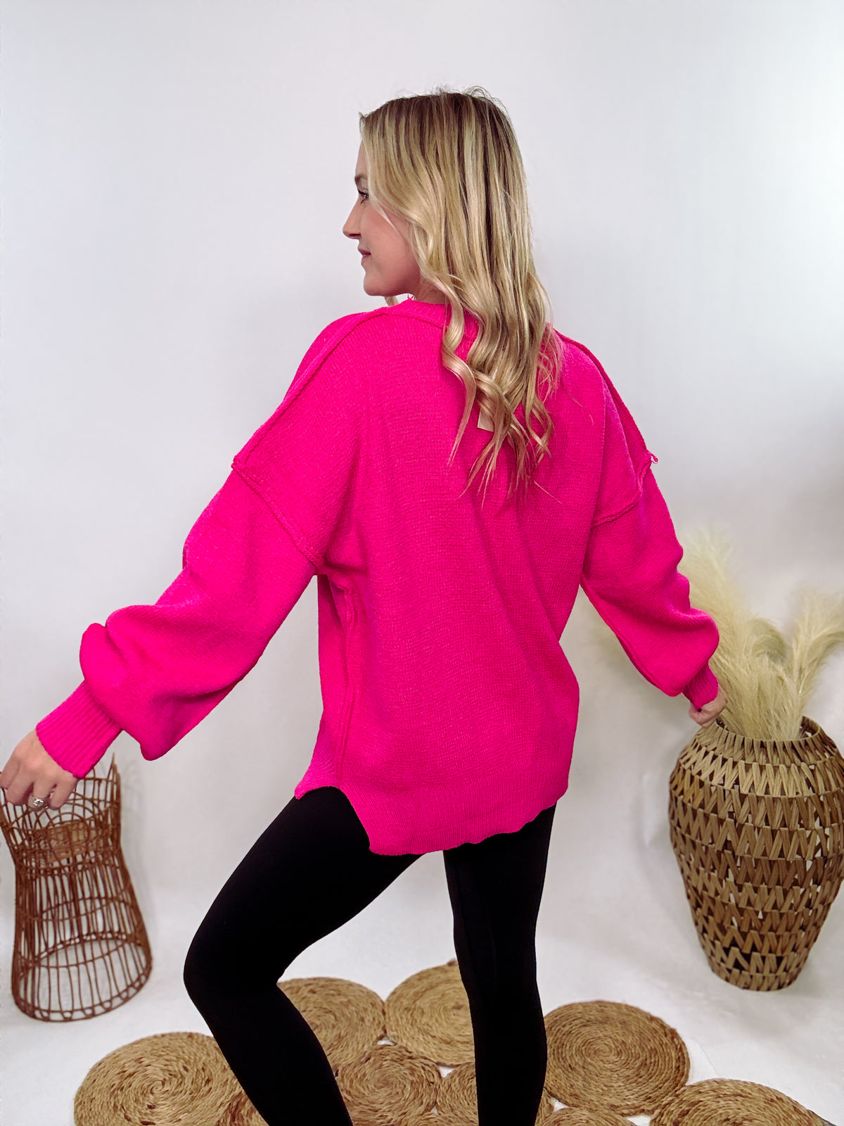 Hot pink oversized sweater with exposed seams, side slits, and a ribbed hem. Cozy, stylish, and perfect for brightening up your winter wardrobe.