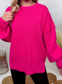 Hot pink oversized sweater with exposed seams, side slits, and a ribbed hem. Cozy, stylish, and perfect for brightening up your winter wardrobe.