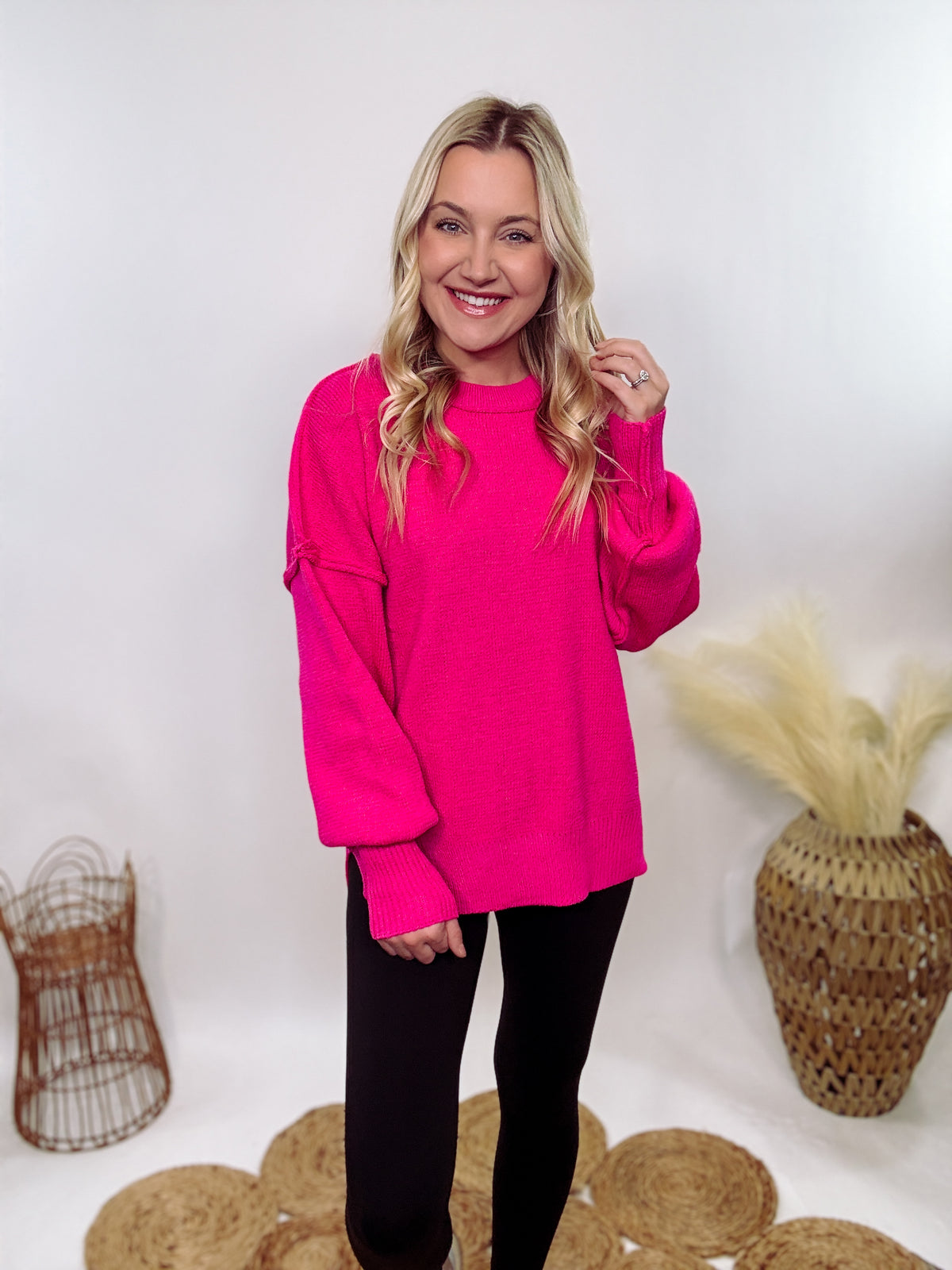 Hot pink oversized sweater with exposed seams, side slits, and a ribbed hem. Cozy, stylish, and perfect for brightening up your winter wardrobe.