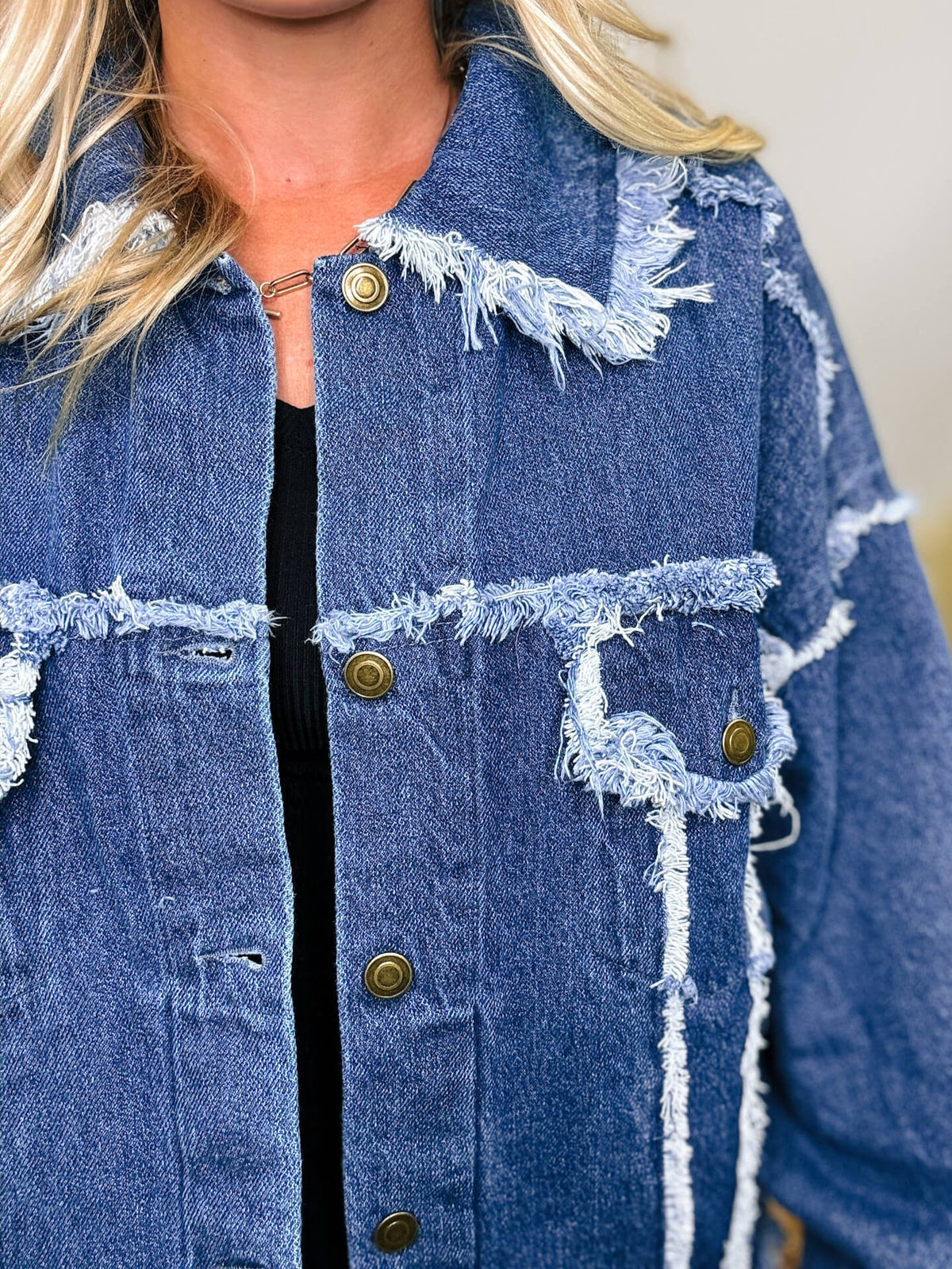 Oversized frayed hem denim jacket with exaggerated frayed hems and seams, styled over black biker shorts and a black ribbed baby tee.