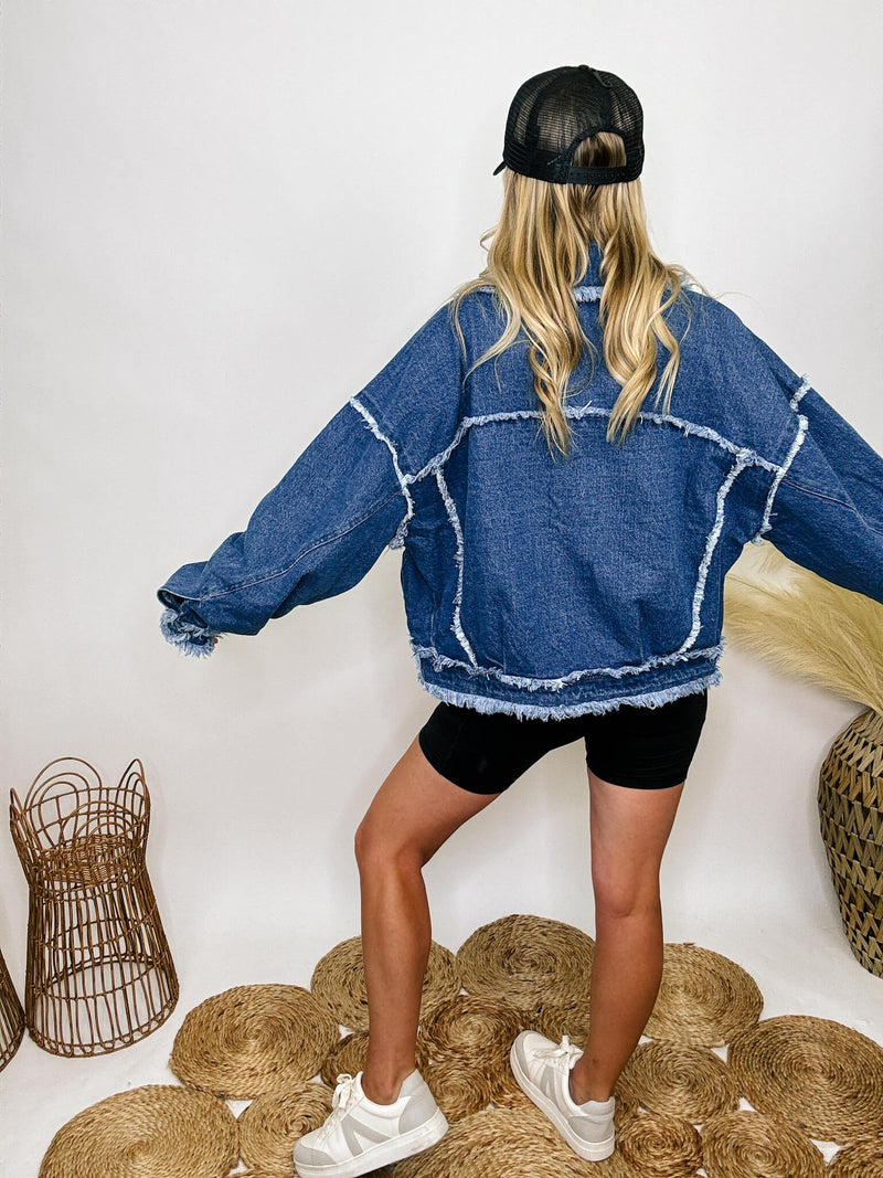 Oversized frayed hem denim jacket with exaggerated frayed hems and seams, styled over black biker shorts and a black ribbed baby tee.