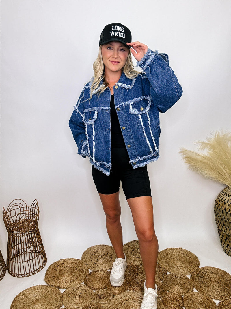 Oversized frayed hem denim jacket with exaggerated frayed hems and seams, styled over black biker shorts and a black ribbed baby tee.