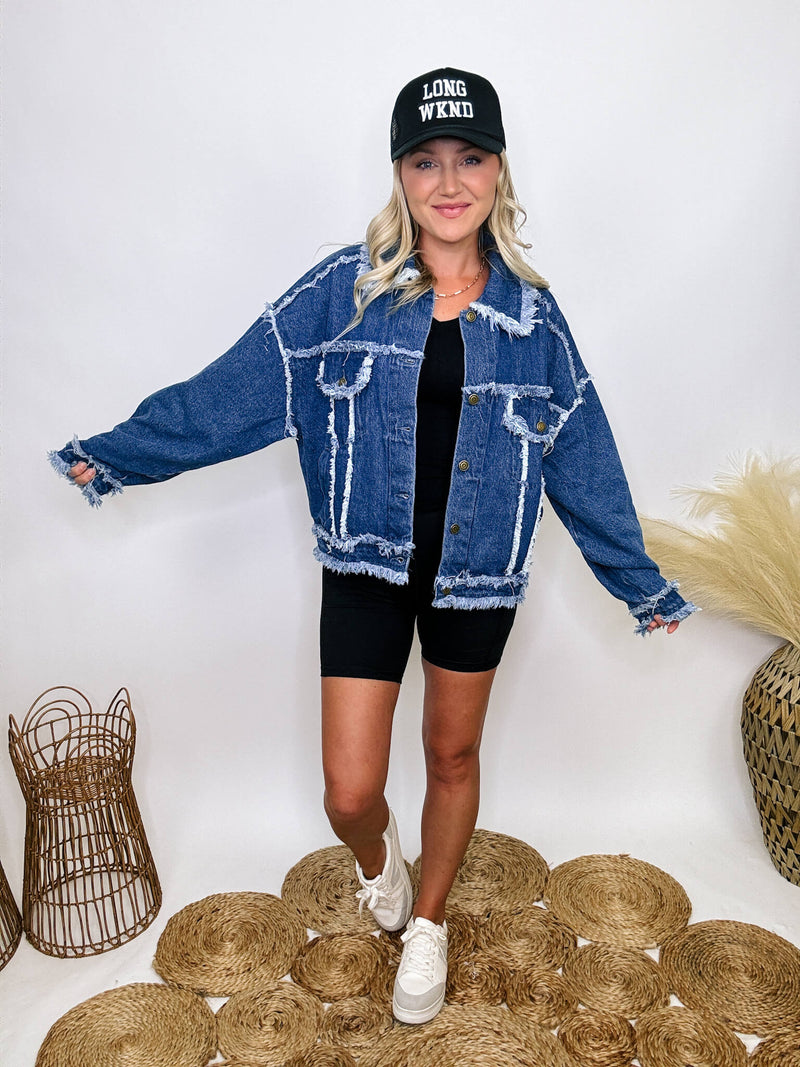 Oversized frayed hem denim jacket with exaggerated frayed hems and seams, styled over black biker shorts and a black ribbed baby tee.