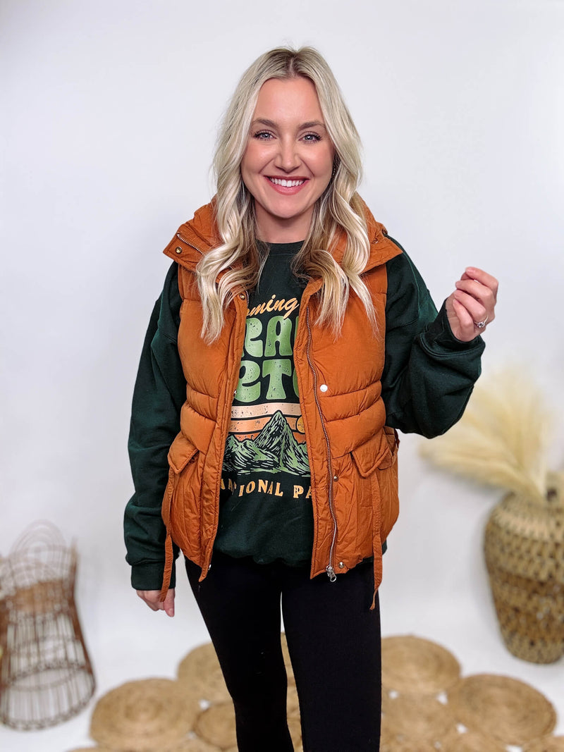 Shop the Rusty Burnt Orange Cargo Puffer Vest at Bmaes Boutique. Made from 100% polyamide, this stylish and versatile vest features two flap pockets and is perfect for layering over sweatshirts or tees.