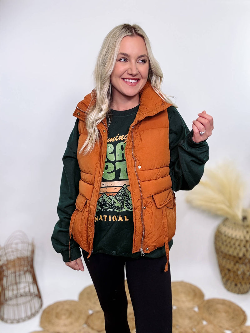 Shop the Rusty Burnt Orange Cargo Puffer Vest at Bmaes Boutique. Made from 100% polyamide, this stylish and versatile vest features two flap pockets and is perfect for layering over sweatshirts or tees.