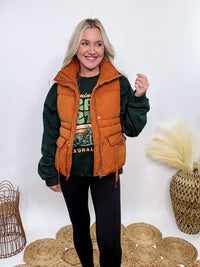 Shop the Rusty Burnt Orange Cargo Puffer Vest at Bmaes Boutique. Made from 100% polyamide, this stylish and versatile vest features two flap pockets and is perfect for layering over sweatshirts or tees.