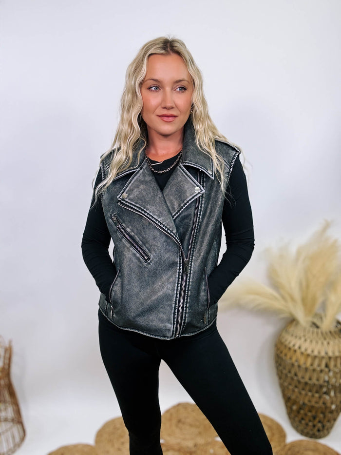 Washed black PU leather moto vest with notched lapels, silver zippers, and shoulder epaulets, perfect for layering.