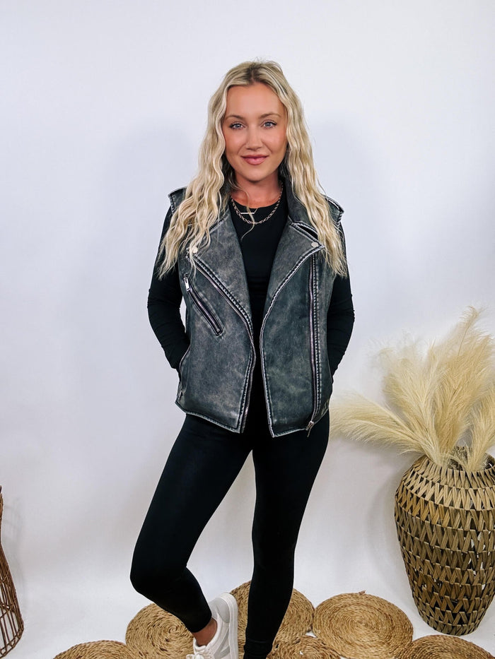 Washed black PU leather moto vest with notched lapels, silver zippers, and shoulder epaulets, perfect for layering.