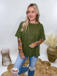 In Loom Oversized olive green tee with layered sheer embroidered floral lace mesh sleeves. Relaxed fit, earthy olive tone, and high-quality fabric blend. Perfect for casual fall outfits or dressing up with jeans or leather leggings. Feminine and edgy design ideal for crisp autumn days.