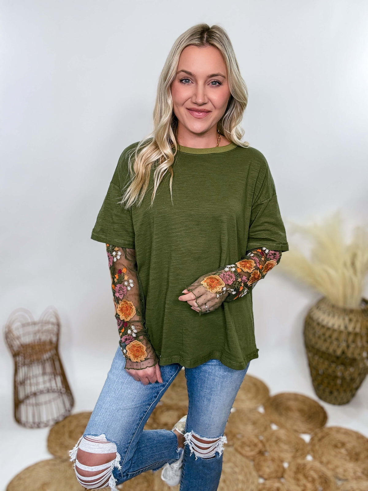 In Loom Oversized olive green tee with layered sheer embroidered floral lace mesh sleeves. Relaxed fit, earthy olive tone, and high-quality fabric blend. Perfect for casual fall outfits or dressing up with jeans or leather leggings. Feminine and edgy design ideal for crisp autumn days.